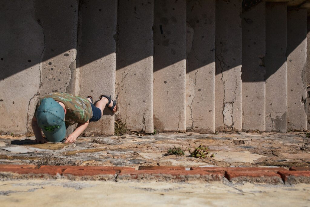 a person kneeling on the ground in front of a wall